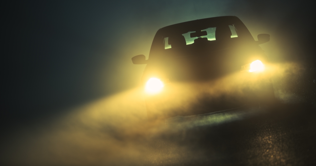 Car in fog with working headlights